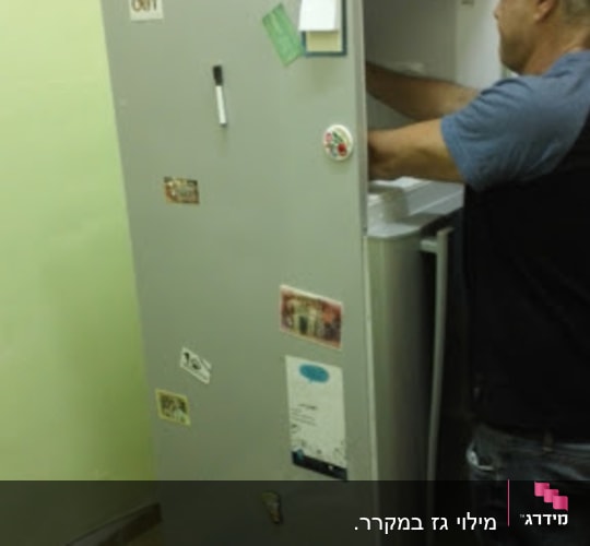 אדם מתקן מקרר עם כלים וחלקים